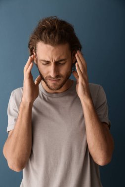 Arka planda baş ağrısı çeken genç bir adam