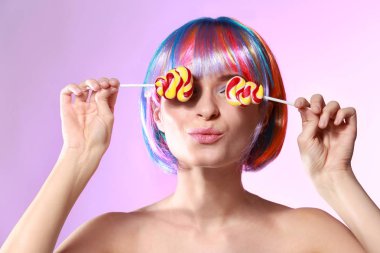 Tatlı lolipop ve peruk renk arka plan üzerinde olan güzel kadın