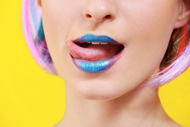 Renkli arka planda olağandışı makyajı olan güzel bir genç kadın. Yakın plan.