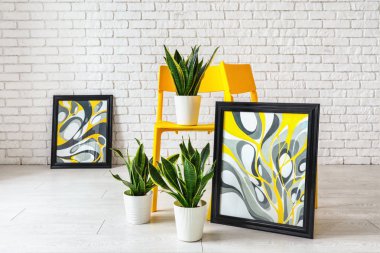 Odada sandalye houseplants ve resimler yakınındaki beyaz tuğla duvar