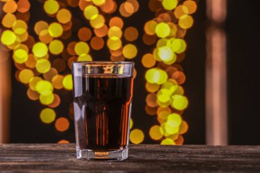 Lezzetli cola içecek bulanık ışıklar karşı ahşap masa üzerinde bardak