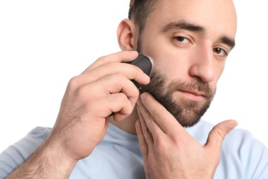 Beyaz arka plan karşı elektrikli tıraş makinesi kullanan yakışıklı adam