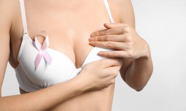 Genç kadın güzel meme ve ışık arka plan üzerinde pembe kurdele ile. Kanser farkındalık kavramı