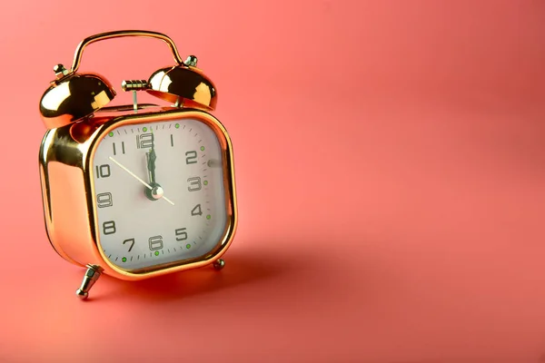 Golden alarm clock on color background