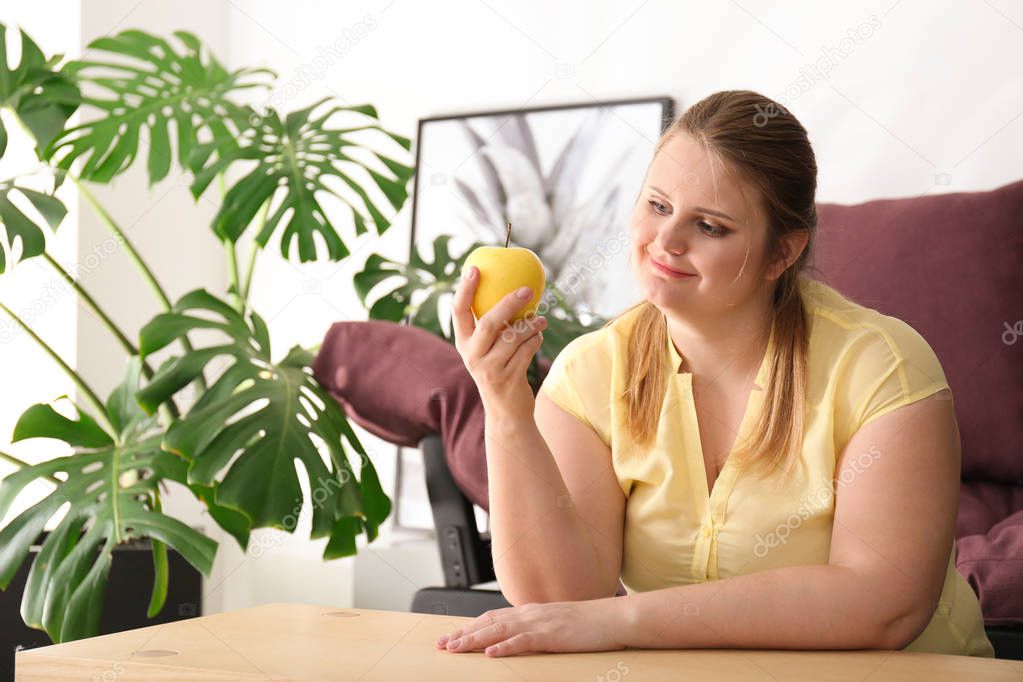 Beautiful plus size girl with apple at home. Concept of body positivity