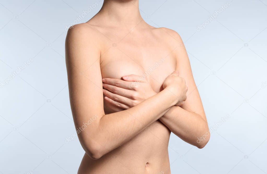 Young woman with beautiful breast on light background