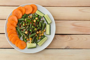 Ahşap masa, üstten görünüm üzerinde taze sebze salatası ile plaka. Diyet gıda