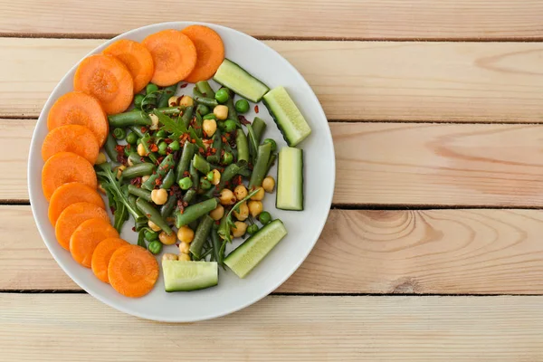 Ahşap masa, üstten görünüm üzerinde taze sebze salatası ile plaka. Diyet gıda