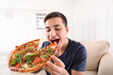 Genç adam evde lezzetli pizzalar yiyor.