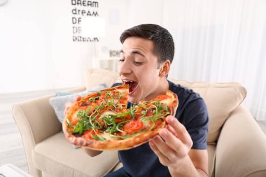 Genç adam evde lezzetli pizzalar yiyor.