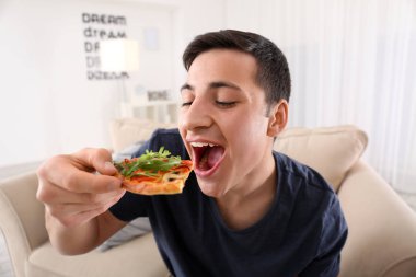 Genç adam evde lezzetli pizzalar yiyor.