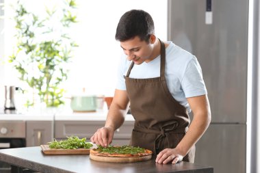 Genç adam masada lezzetli pizza dekorasyon