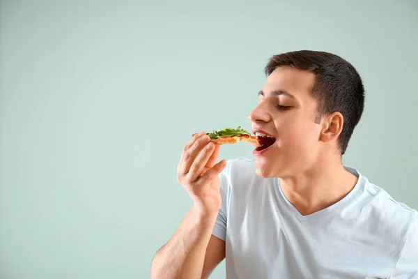 Νεαρός Άνδρας Τρώει Νόστιμο Πίτσα Επάνω Ελαφρύς Υπόβαθρο — Φωτογραφία Αρχείου