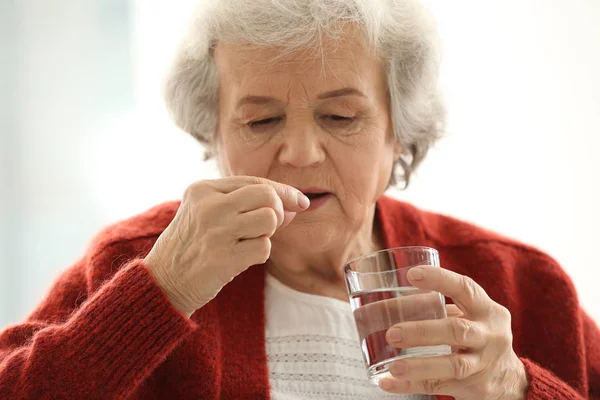 Elderly Woman Taking Pill Light Background — Stock Photo, Image