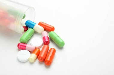 Beyaz arka plan üzerinde renkli haplarla konteyner