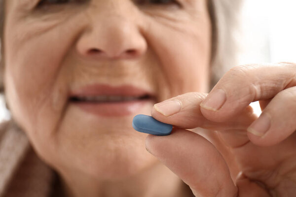 Elderly woman taking pill, closeup