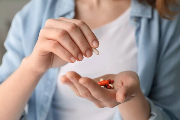 Young woman holding different pills, closeup