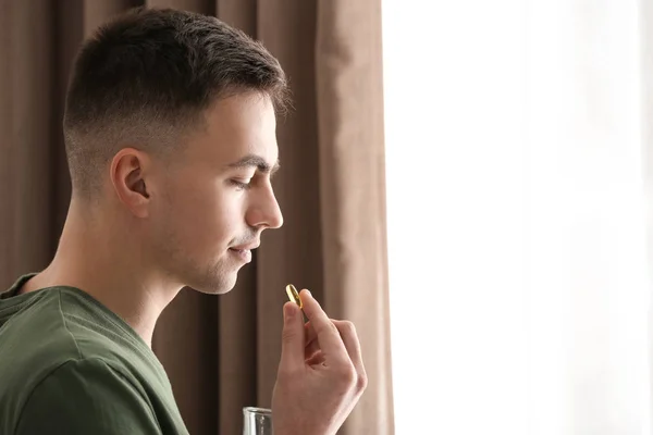 Young Man Taking Pill Indoors — Stock Photo, Image