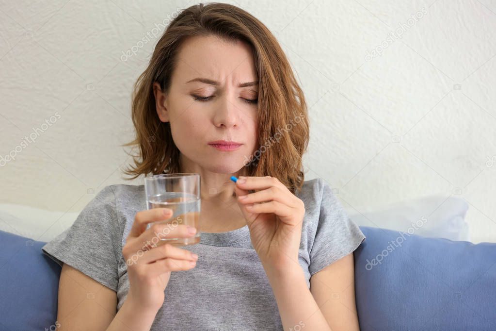 Young woman taking pill in bed