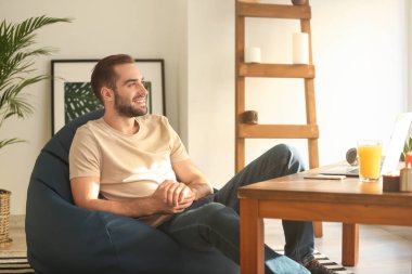 Evde beanbag sandalye üzerinde oturan genç adam