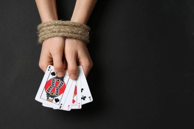 Ve kadın ile berabere kalan eller iskambil koyu arka plan üzerinde. Bağımlılık kavramı