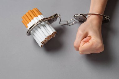 Kadın sigara gri arka plan üzerinde kelepçeli. Bağımlılık kavramı