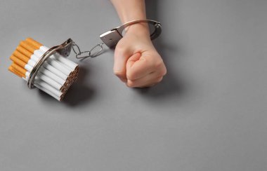 Kadın sigara gri arka plan üzerinde kelepçeli. Bağımlılık kavramı