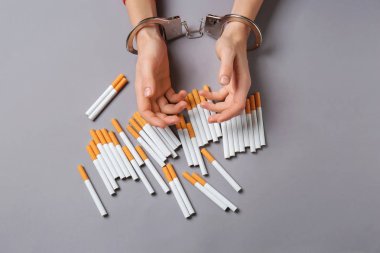 Kadın gri arka plan üzerinde sigara ile kelepçeli. Bağımlılık kavramı