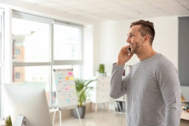 Genç tasarımcı ofis cep telefonunda konuşuyor