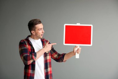 Boş tahta gri arka plan üzerinde olan genç adam