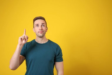 Renk arka plan üzerinde yükseltilmiş işaret parmağı ile genç adam
