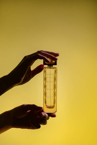 Woman holding bottle of perfume on color background