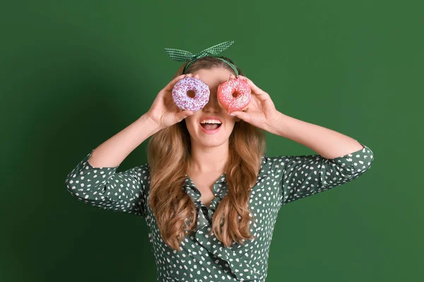 色の背景上のおいしいドーナツを持つ面白い若い女性 — ストック写真