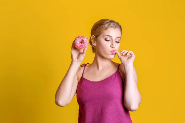 滑稽的年轻女人 与美味甜甜圈上颜色背景 — 图库照片