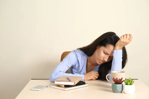 Stressed young woman sitting at table in office