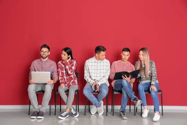 Jóvenes Estudiantes Sentados Cerca Pared Color —  Fotos de Stock
