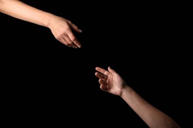 Female hands reaching out to each other on dark background clipart