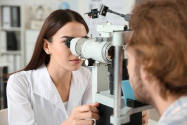 Klinikte genç adam inceleyerek göz doktoru