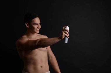 Koyu arka plan deodorant ile genç adam