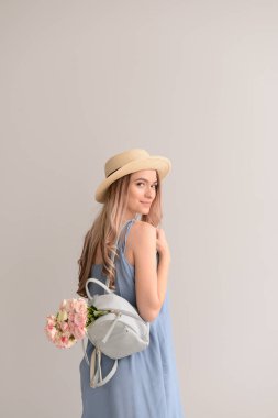 Buket çiçek ve sırt çantası gri arka plan üzerinde olan güzel kadın