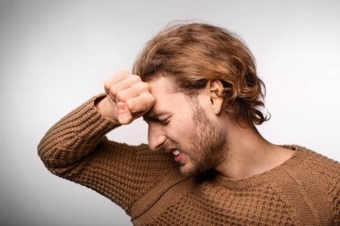 Genç adam ışık arka plan üzerinde baş ağrısı muzdarip