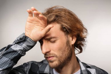 Genç adam ışık arka plan üzerinde baş ağrısı muzdarip