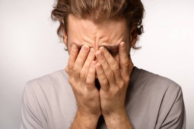 Genç adam ışık arka plan üzerinde baş ağrısı muzdarip