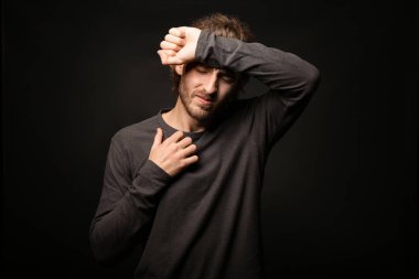 Genç adam koyu arka plan üzerinde baş ağrısı muzdarip