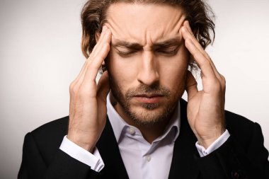 Genç işadamı ışık arka plan üzerinde baş ağrısı muzdarip