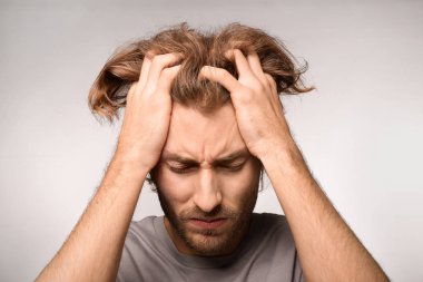 Genç adam ışık arka plan üzerinde baş ağrısı muzdarip