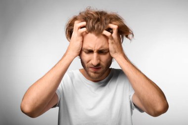 Genç adam ışık arka plan üzerinde baş ağrısı muzdarip