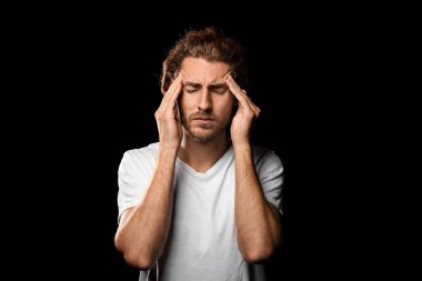 Genç adam koyu arka plan üzerinde baş ağrısı muzdarip