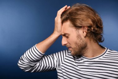 Arka planda baş ağrısı çeken genç bir adam