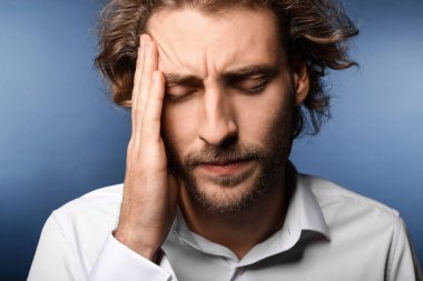 Arka planda baş ağrısı çeken genç bir adam